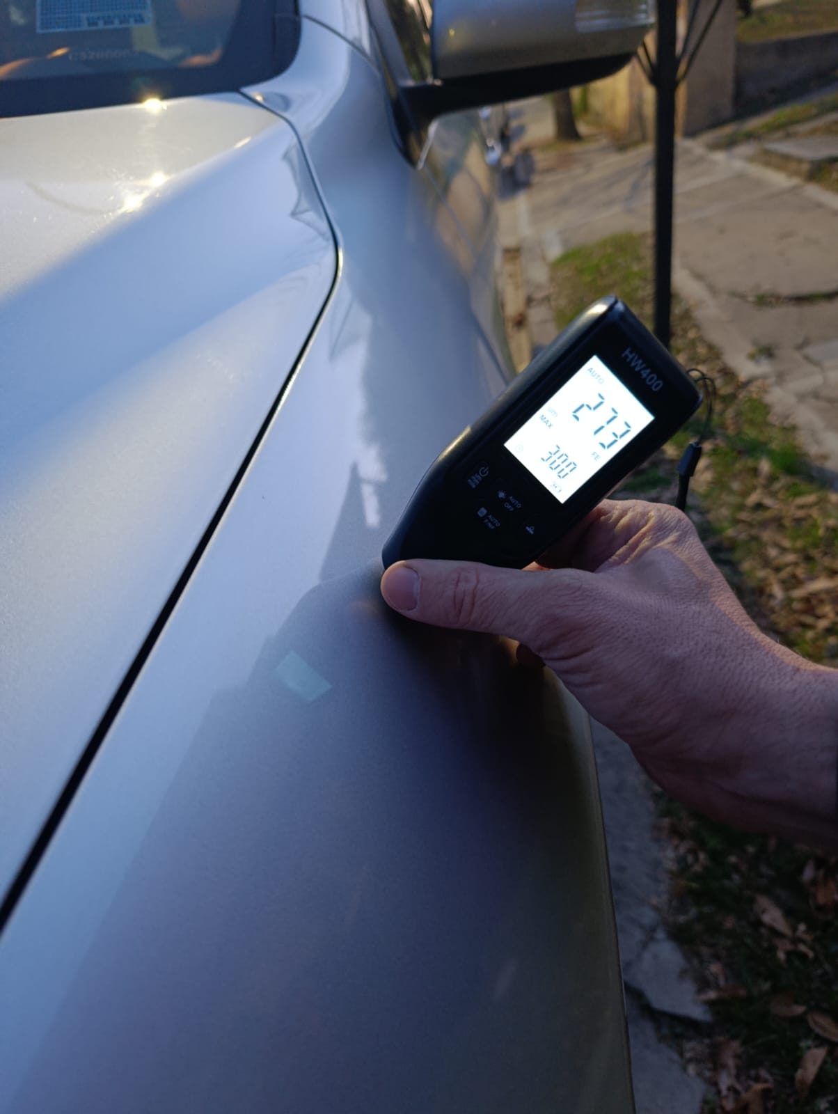 Perito midiendo el espesor de pintura de un auto con instrumento